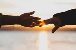 Sun,shines,behind,hands,of,man,and,woman,reaching,fingers - Jonathan Olvera Counseling Hands reaching to connect.